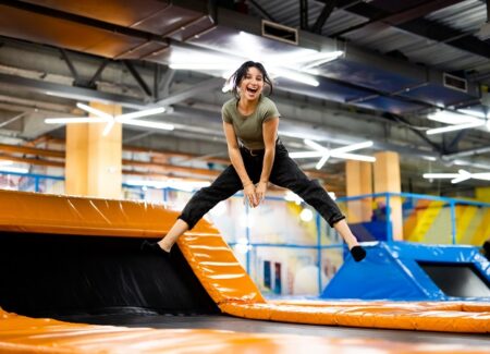 Eine Frau springt auf einem Trampolin in einer Trampolinhalle.