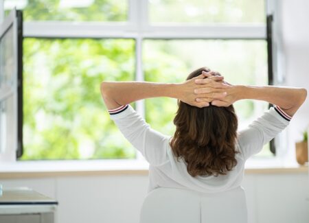 Eine Frau sitzt vor einem geöffneten Fenster