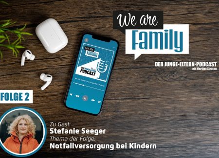 Auf einer Holzfläche steht ein Smartphone mit dem Cover des We-are-family-Podcastes