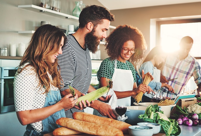 Mehrere Personen stehen am Herd und kochen miteinander